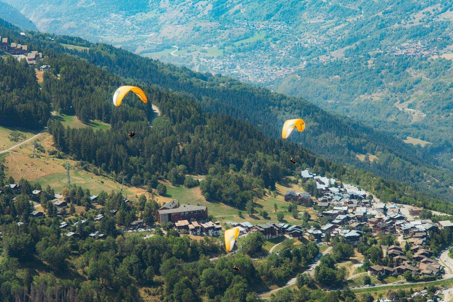 Parapentes survolant un village de montagne alpin