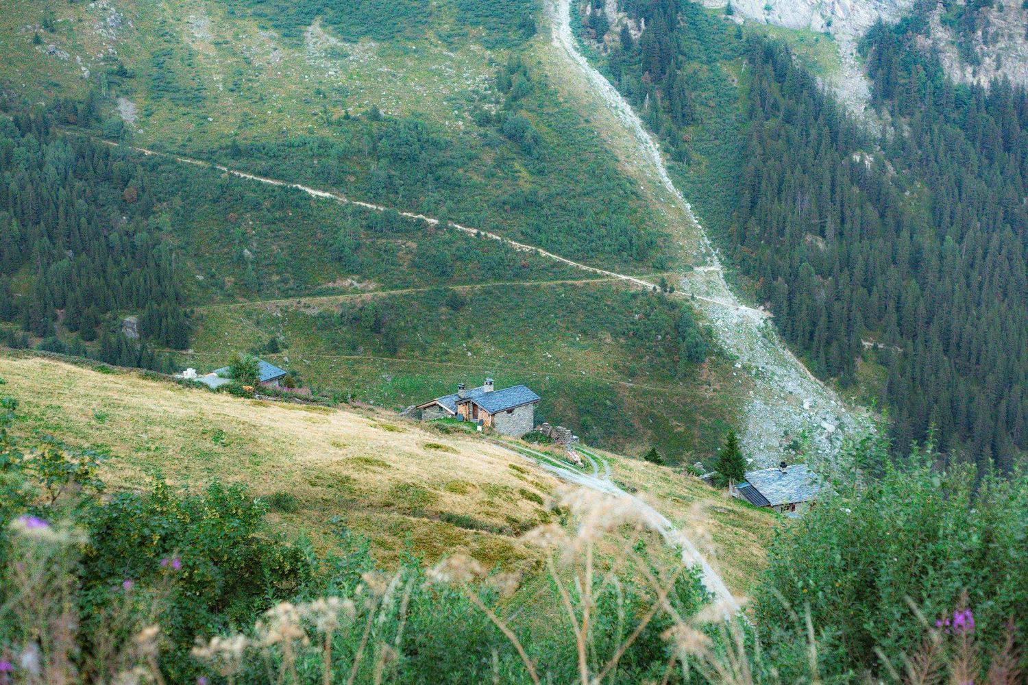 Sentier de montagne redescendant vers un hameau alpin