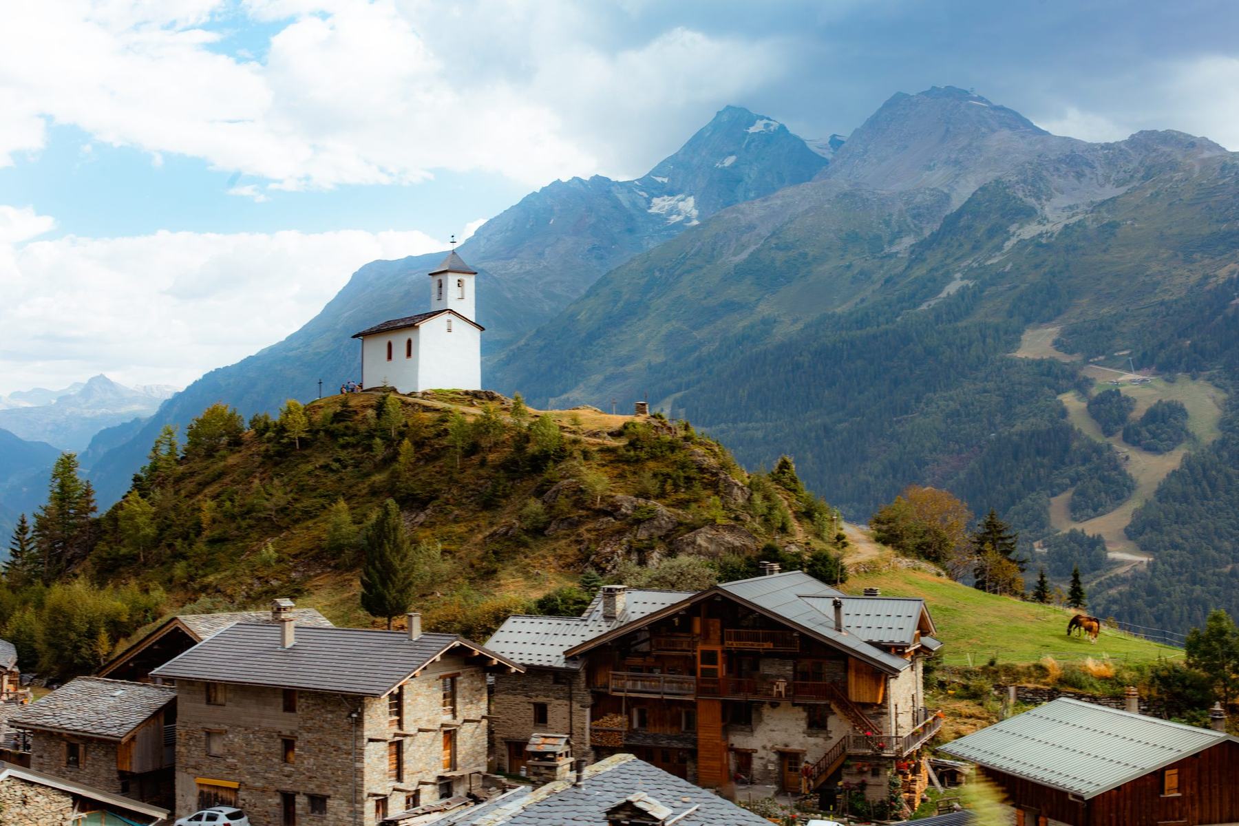 Village de montagne avec chapelle, vu depuis un sentier de randonnée